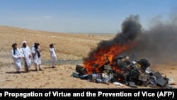 Members of the Taliban morality police stand beside a bonfire of musical instruments and equipment they confiscated and burned in the Western Afghan city of Herat on July 29.