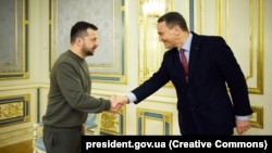 Radosław Sikorski (d.) la Kiev, în decembrie 2023, dând mâna cu președintele ucrainean Volodimir Zelenski.