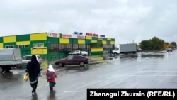 Женщина в никабе идет с ребенком к рынку в Актобе. 6 октября 2023 года