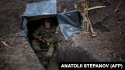 Украинский пехотинец 57-й отдельной мотопехотной бригады сидит в окопе на востоке Украины