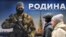 Люди проходят мимо стенда с изображением российского военнослужащего и надписью "Родину, которую мы защищаем" на уличной выставке плакатов на военную тематику в центре Санкт-Петербурга 