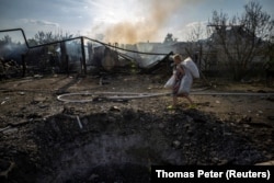 Жінка проходить повз кратер, що лишився після російського удару по приватному сектору у Покровську, 3 серпня 2025 року