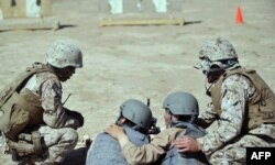 Afghan police officers are advised by U.S. Marines on the use of a Kalashnikov light machine gun during a group shooting lesson at Camp Leatherneck in Helmand Province in 2012.