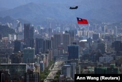 A Taiwanese flag is carried by a Chinook helicopter during a rehearsal for the upcoming National Day celebration in Taipei in October 2021.