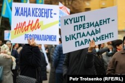 Участники митинга в поддержку президента Касым-Жомарта Токаева закрывают лица транспарантами. Алматы, 19 марта 2022 года