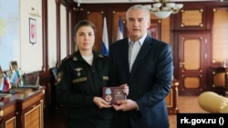 Російський глава Криму Сергій Аксьонов вручає орден «За вірність обов'язку» заступниці командира батальйону 126-ї окремої гвардійської бригади берегової оборони ЧФ Росії Юлії Петраковій, 15 квітня 2022 року