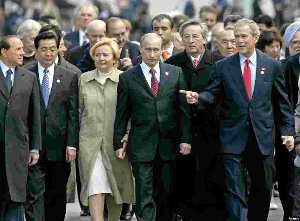 Премьер-министр Италии Сильвио Берлускони; глава Китая Ху Цзиньтао; президент Путин и его супруга Людмила; председатель Европейского союза Жан-Клод Юнкер и президент США Джордж Буш-младший на территории Кремля в Москве после участия в мероприятиях по случаю окончания Второй мировой войны. 9 мая 2005 года 