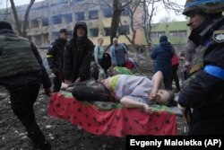 Українські рятувальники і волонтери несуть вагітну жінку, яка постраждала в результаті авіаудару російських військових по пологовому будинку та дитячій лікарні в Маріуполі, 9 березня 2022 року. Пізніше жінка з фото та ї дитина померли