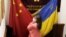 CHINA – A visitor to a Ukraine restaurant holds together the Chinese and Ukraine national flags as she poses for a photo. Beijing, Feb. 24, 2022 