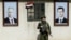 A Russian soldier stands between portraits of Syrian President Bashar al-Assad (right) and Russian President Vladimir Putin at a checkpoint on the outskirts of Damascus in 2018.