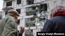 Пожилая пара стоит возле жилого дома в Гуляйполе, поврежденного в результате российской атаки. Запорожская область, 11 ноября 2025 года