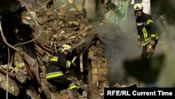 Ратавальнікі разьбіраюць завалы шматпавярховага дома ў Кіеве пасьля расейскага ўдару