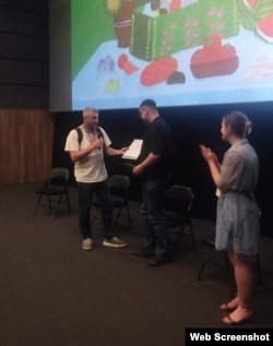 Дмитро Гапченко, працівник Бучанської міської ради вручає подяку журналісту Дмитру Джулаю. Презентація фільму Радіо Свобода «Буча. Яблунська»