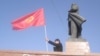 A man waves a Kyrgyz flag next to a statue of Soviet leader Vladimir Lenin in central Osh. City authorities took down the statue in June.