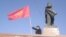 A man waves a Kyrgyz flag next to a statue of Soviet leader Vladimir Lenin in central Osh. City authorities took down the statue in June.
