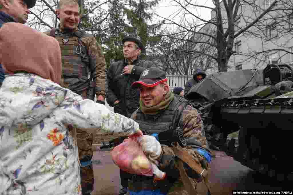 Дівчинка дає кульок із яблуками українському військовому в місті Бахмач Чернігівської області. Звільнення Чернігівщини від російських військ. Квітень 2022 року