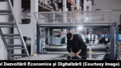 Muncitor într-o hală a unei companii producătoare de articole din inox destinate industriei alimentare și vinicole.