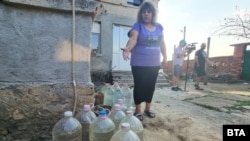 Жителка на хасковското село Александрово показва тубите с вода, които пълнят от съседното село Воден, 24 юли 2025 г.