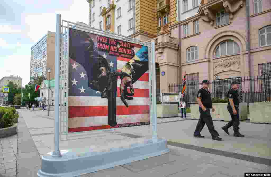 Росія, зі свого боку, також «тролила» західні посольства. На цьому фото – банер біля диппредставництва США в Москві в червні 2024 року.На тлі американського прапора до руки зі зброєю прикована рука, вдягнена в одяг кольорів українського стяга. Над ними – напис «Звільни свого «раба» від його оков» і дата – 19 червня, День визволення рабів (або День свободи) у США