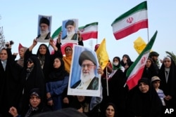 Демонстранты держат флаги Ирана и плакаты с изображением Верховного лидера аятоллы Али Хаменеи на антиизраильском и антиамериканском митинге на площади Энкеляб-е-Эслами (площади Исламской революции) в центре Тегерана, 24 июня 2025 года