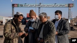 A Taliban fighter checks passports at Afghanistan's Islam Qala border crossing with Iran.