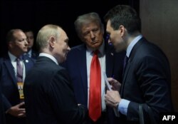 Президент США Дональд Трамп (в центре) и лидер России Владимир Путин (слева) беседуют после совместной пресс-конференции по итогам саммита США и России. Аляска, Анкоридж, 15 августа 2025 года