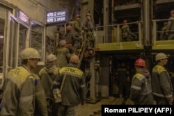 Шахтеры заходят в лифты, чтобы спуститься под землю угольной шахты в западной части Донбасса, октябрь 2024 года