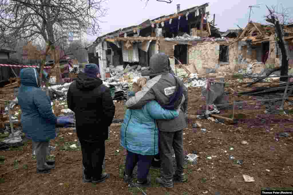 Родина дивиться на зруйнований російським обстрілом будинок у Нових Петрівцях
