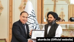 Қазақстан президентінің арнаулы өкілі Ержан Қазыханов (сол жақта) Абдол Ғани  Барадарға 5 мың тонна гумкөмек сертификатын тапсырып тұр