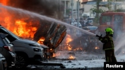 Сотрудник спасательной службы тушит пожар после попадания выпущенной из Газы ракеты по Ашкелону, 7 октября 2023 года
