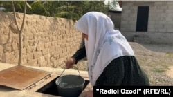 Ҳовлидаги қудуқдан сув олаётган онахон. Хатлон вилояти.