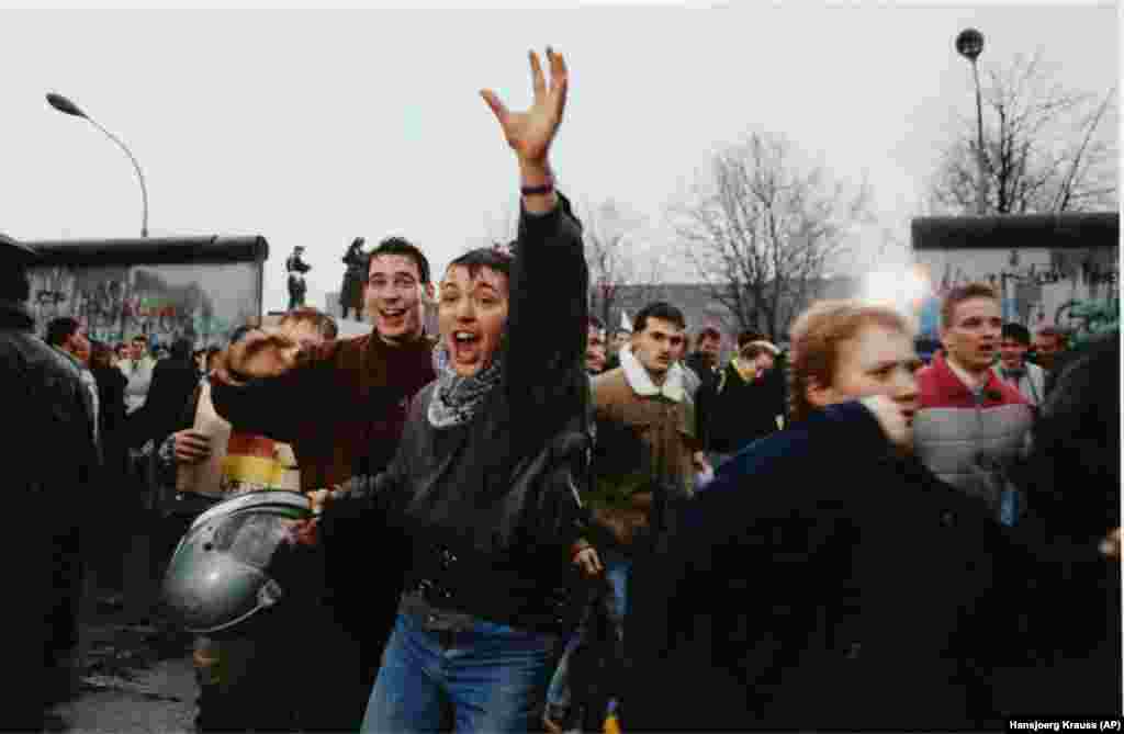 Young East Berliners celebrate as they enter the West through an opening in the Berlin Wall in December 1989.Шығыс Берлиндегі жастар Берлин қабырғасындағы саңылау арқылы Батысқа өткеніне мәз-мейрам болып жатыр. 1989 жылғы желтоқсан.Берлин қабырғасы құлаған соң, Еуропадағы тағы коммунистік режим ыдырады. Осы кезде Азат Еуропа/Азаттық радиосының болашағы жайлы талқы туып, радио бюджетінің үштен екісіне жуығы қысқарды.