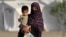 An Afghan woman holds a child as she arrives from Pakistan at a makeshift camp near the Afghanistan-Pakistan Torkham border in Nangarhar Province on April 20.