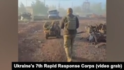 Военнослужащий 7-го Корпуса быстрого реагирования Украины идет за наземным беспилотником в городе Покровск. Скриншот с видео