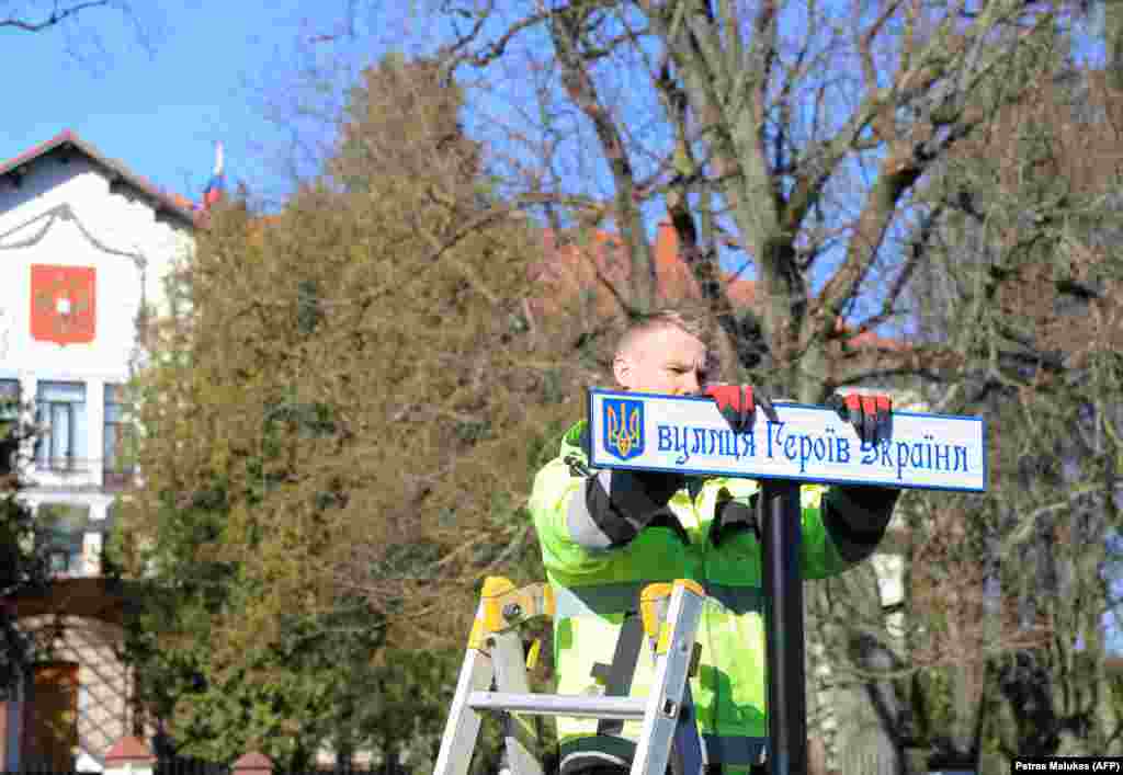 Вільнюс, Литва, березень 2022 року. Прямо перед російським посольством (його видно на задньому плані) робітник встановлює вуличний знак з новою назвою дороги, що веде до диппредставництва РФ. Тепер це – вулиця Героїв України