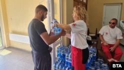 Хора от Червения кръст раздават бутилирана вода на жителите на Брезник, 12 юли 2025 г.