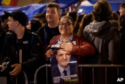 Сторонница Никушора Дана прижимает к груди его предвыборный плакат. Бухарест, вечер 18 мая 2025 года