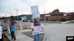 A protester holds signs outside an Immigration and Customs Enforcement (ICE) facility in Broadview, Illinois, on October 1