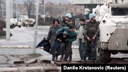 غیر نظامیان ساکن سارایوو پشت یک خودروی زرهی سازمان ملل متحد پناه گرفته‌اند