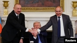 Қол алысып тұрған Әзербайжан президенті Илхам Әлиев пен Армения премьер-министрі Никол Пашинян. АҚШ президенті Дональд Трамп оларды бітістіріп отыр. Вашингтон, 8 тамыз, 2025 жыл.