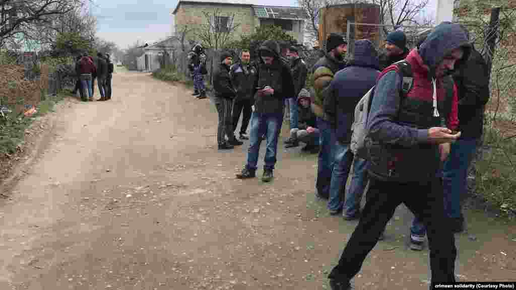 Yerli sakinler ve faaller tintüvler keçirilgen evlerniñ yanında toplaşa