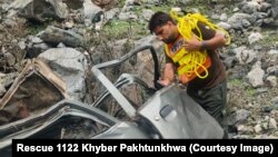 په کوهستان کې د رېسکیو ۱۱۲۲ یو کارکوونکی کندې ته له پرېوتي ګاډي څخه د ژوبلو کسانو ایستلو هڅه کوي - د مې لومړۍ انځور.