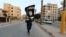 A member of the Islamic State militants waves an IS flag in the Syrian city of Raqqa. (file photo)