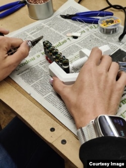 Женщина в львовской мастерской склеивает аккумуляторы для вейпов, отправленные из Лидса. После сборки их поместят во внешний аккумулятор