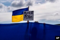 Протестувальник тримає український прапор і плакат під час мітингу в Анкориджі, Аляска, у четвер, 14 серпня 2025 року, напередодні зустрічі президента Дональда Трампа і президента Росії Володимира Путіна