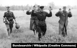 Немецкий военный (слева) и советские пленные в первые дни войны Германии против СССР, июнь 1941 года