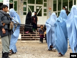 Afghan policeman stands guard as burqa-clad women leave after attending a seminar on domestic violence in Herat. November 24, 2009