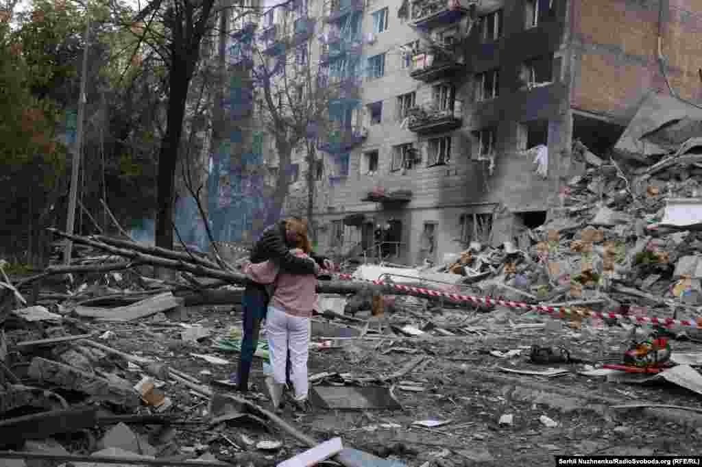 Подружжя біля зруйнованого будинку у Києві. Під завалами, ймовірно, знаходиться їхній син