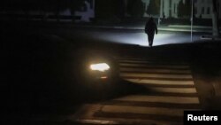 Прохожий идет по улице в Харькове, освещая путь фонариком, 9 ноября 2025 года