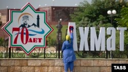 Уборщица на фоне городских украшений в честь 70-летия Ахмата Кадырова, архивное фото